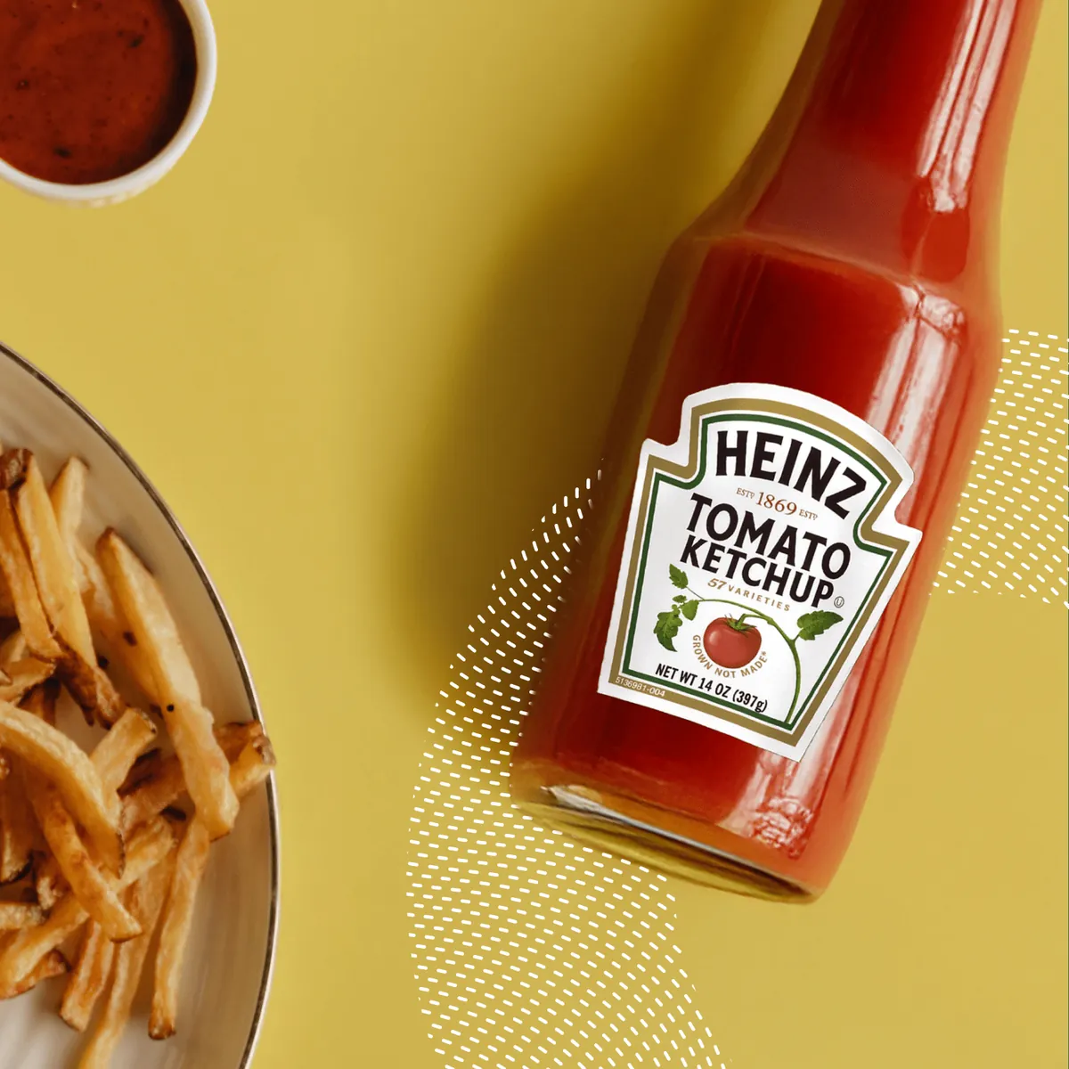 A bottle of Heinz tomato ketchup beside a plate of fries