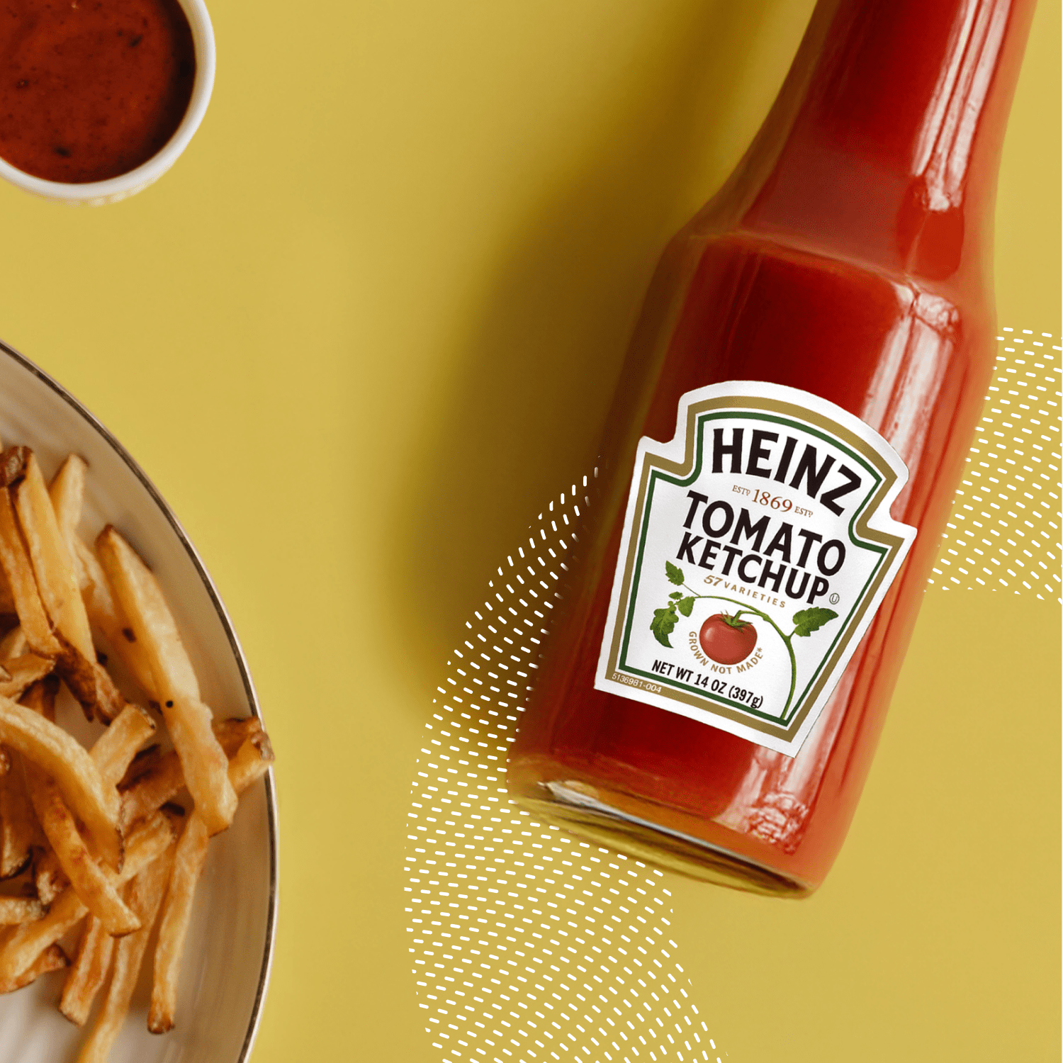 A bottle of Heinz tomato ketchup beside a plate of fries